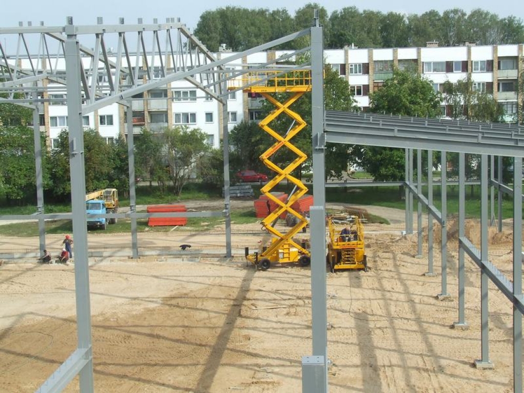 Apveids redzams. Sporta halles karkass jau pārsniedz pie ģimnāzijas augošo koku galotnes, un jaunbūvi var ieraudzīt arī no ielas puses.    