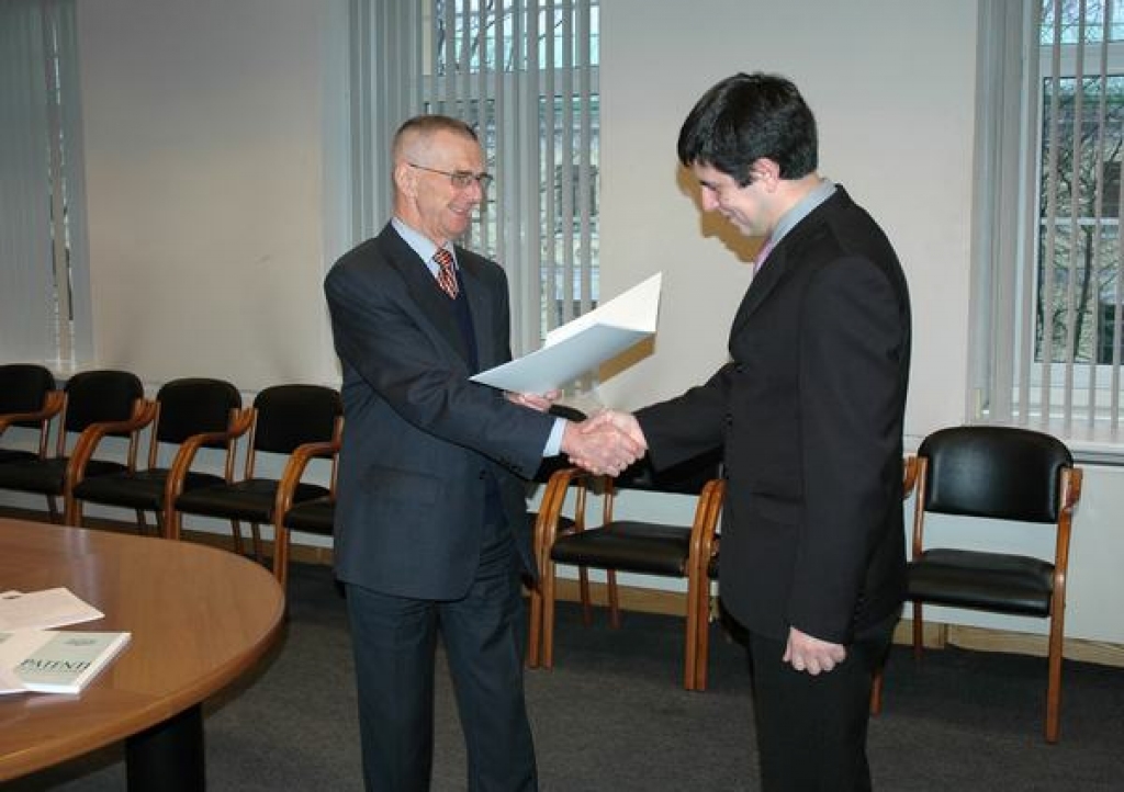 Apliecinājums. Patentu valdes direktors Zigrīds Aumeisters (pa kreisi) pasniedz preču zīmes reģistrācijas apliecību  DK “Daugava” pārstāvim Kasparam Ēvelim.