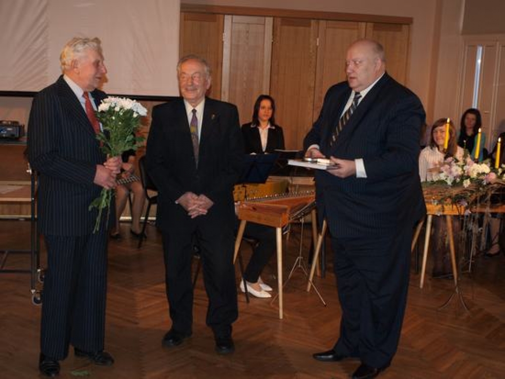 Trīs vīri plāniņa vidū. Alfrēds Jānis Kampe (pa kreisi) no “dzelžiem” gatavo sadzīvē noderīgus mehānismus un palīdz skrīveriešiem apstrādāt mazdārziņus. Viņu sveic vēstules autors Roberts Paegle (vidū) un Aizkraukles rajona padomes priekšsēdētājs Pēteris Keišs.  