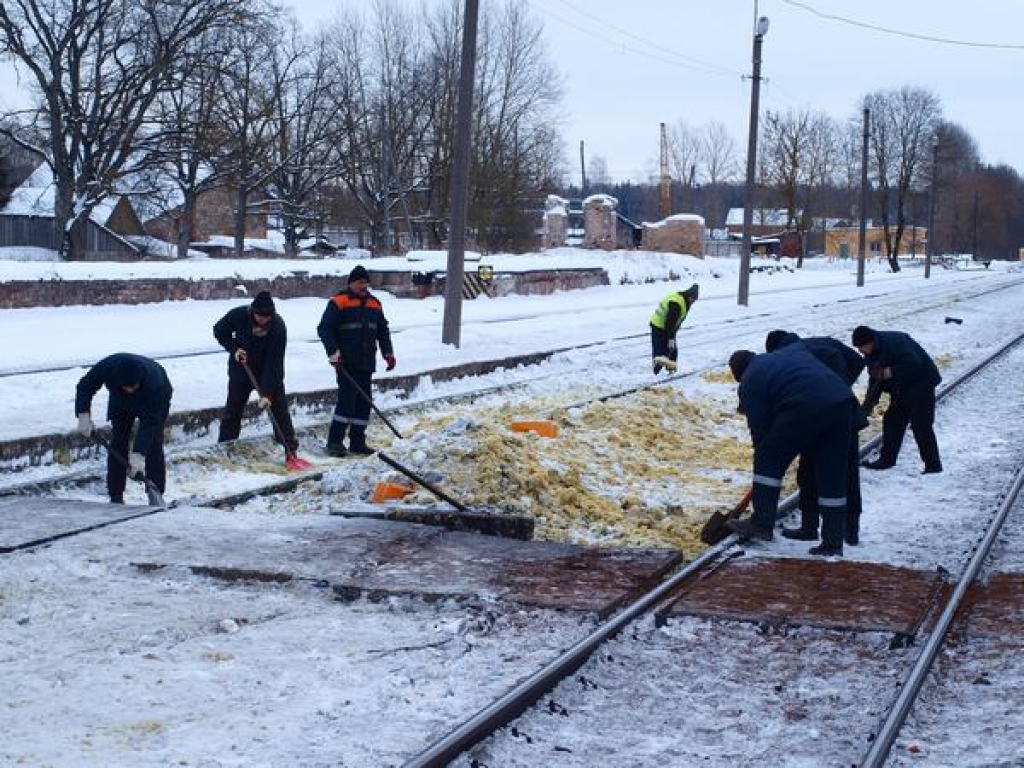 EĻĻAINS SNIEGS. “Latvijas dzelzceļa” strādnieki Kokneses stacijā savāc ar sniegu sajaukto izlijušo dīzeļeļļu.   