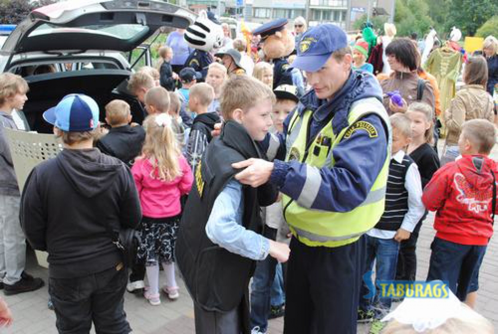 SMAGA. Zēniem visvairāk patika izmēģināt policistu ekipējumu. Policijas inspektors Raivis Pētersons palīdz pielaikot bruņuvesti.