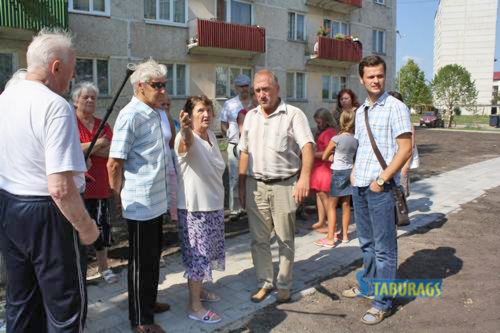 MUMS VAJAG MIERU! “Bērni trokšņos un neļaus mums gulēt, šūpoles vajag aizvākt!” žestikulējot gan ar rokām, gan spieķi, pašvaldības izpilddirektoram Eināram Zēbergam (otrais no labās) un projekta autoram Edvīnam Tolmanim (no labās) pieprasa pensionāru grupa. 