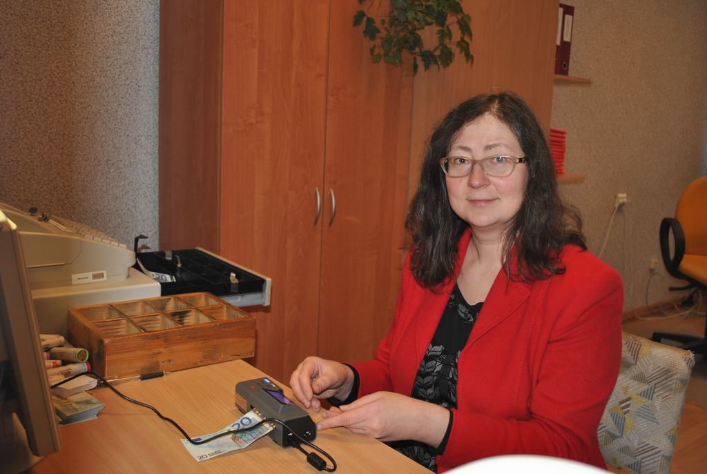 JĀSTRĀDĀ DIVTIK VĒRĪGI. Ar speciālas ierīces palīdzību Līga Grudule var pārbaudīt katru eiro banknoti. 
Autors: Sandra Pumpure