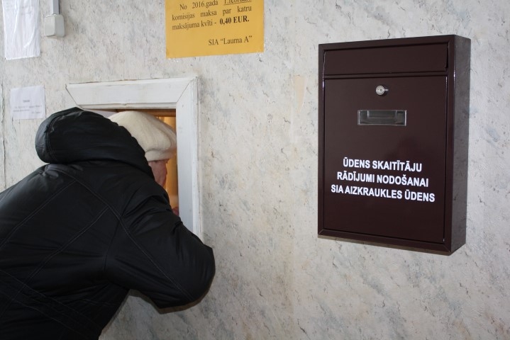 JĀUZRAKSTA UZ LAPIŅAS UN JĀPAZIŅO. Daļa pilsētas iedzīvotāju par ūdeni  norēķinās pašvaldības uzņēmuma “Lauma A” kasē. Tagad pie tās ir novietota arī pastkaste ūdens skaitītāju rādījumu paziņošanai — šo iespēju izmanto galvenokārt tie, kuriem nav datora un interneta.
Autors: Guna Mikasenoka 