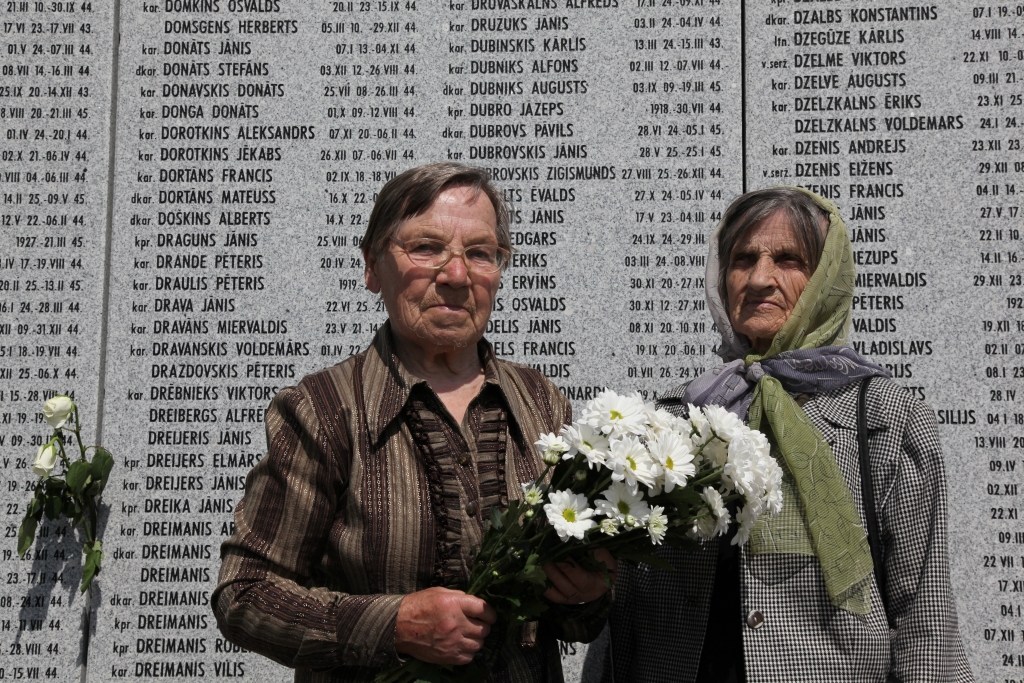 Jūlija Smane ar radinieci Skolastiku Utināni pie sienas, kurā iegravēti bojā gājušo leģionāru, kā arī viņu radinieka Jāņa Družuka vārdi.   
Autors: Žanna Žaka