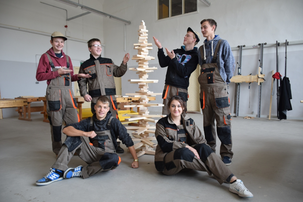 NEPARASTĀ, NETRADICIONĀLĀ. Šādus vārdus Aizkraukles Profesionālās vidusskolas pirmā kursa audzēkņi velta eglei, kuru uztaisīt bijis ļoti grūti, pat “sīvi”, jo vajadzēja strādāt bez elektrības, tikai ar rokas instrumentiem. Priekšplānā — Rūta Tumova un Aldis Korņejevs, Jānis Mucenieks (stāv no kreisās),  Raimonds Rancāns, Aleksandrs Ivolga un Viesturs Mazulis. 
Autors: Guna Mikasenoka