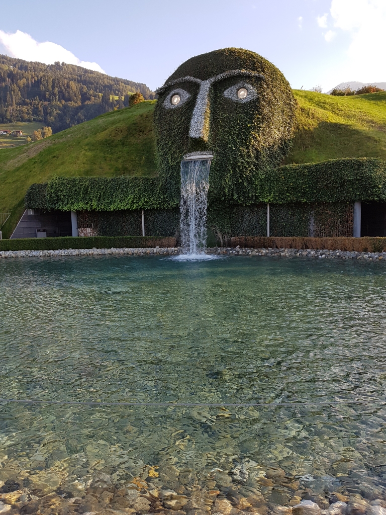 POPULĀRĀKAIS SKATS uz Svarovska muzeju, kas īstenībā ir pazemē. Zem zaļā paugura — cilvēks ar kristāla acīm, bet vārdu plūsmas vietā — 
kalnu ūdens.