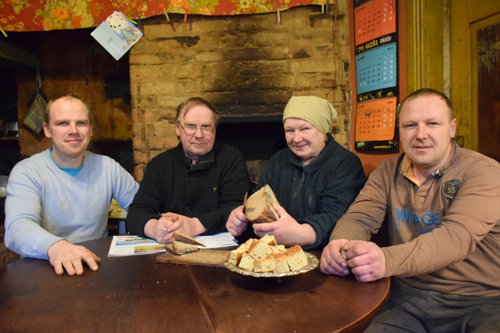 NEKĀ JAU NEPIETRŪKST. Baltaču ģimene — Kaspars (no kreisās), Jānis, Ausma un Zigmunds — atelpas brīdī pie saimes galda ar mammas cepto maizes klaipu. Fonā — 1934. gadā būvētā maizes krāsns, kas ir neaizvietojams palīgs arī šodien.
Autors: Imants Kaziļuns