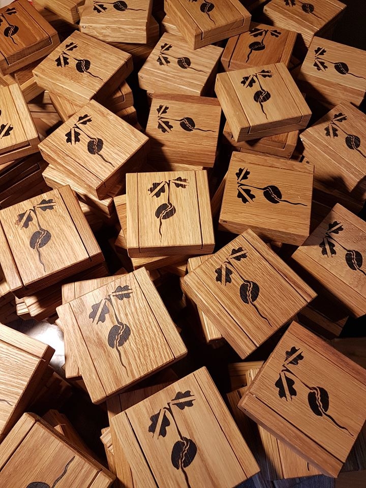 Latvijā auguša ozolkoka kastīte ar projekta “Simtgades bērni” logo — dīgstoša zīle ar karoga siluetu ozola lapās, kas simbolizē dzīvības sākotni ar piederību zemei, kurā nākam pasaulē.