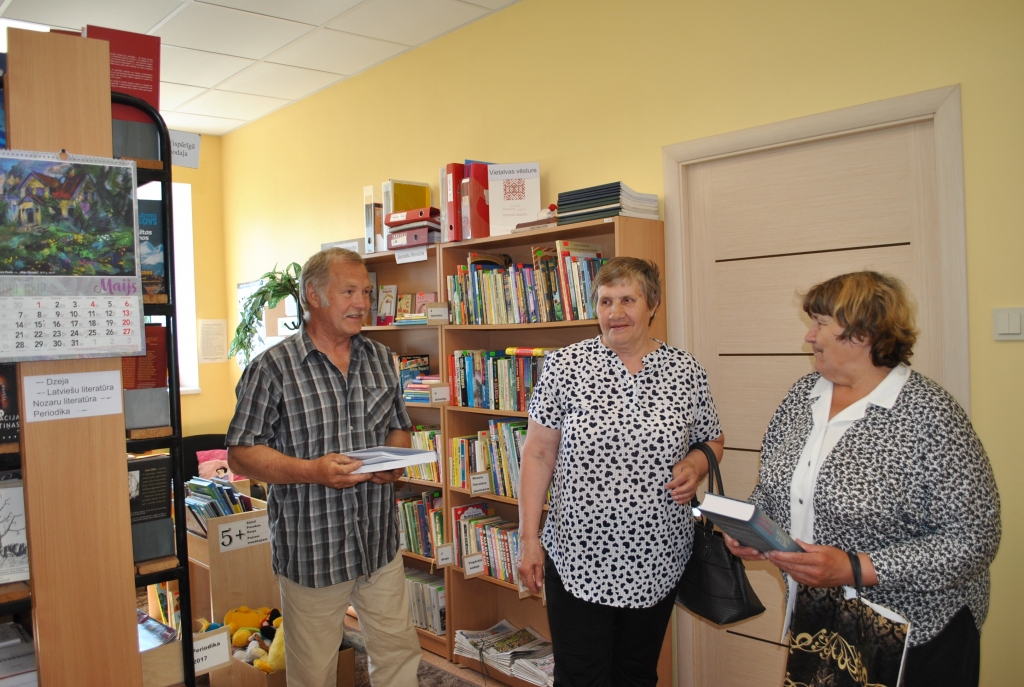 LASĪTĀJI IR. Bibliotēkas vadītājs Jānis Usāns ar bibliotēkas piedāvājumu iepazīstina vietalvietes Tatjanu (no labās) un Mariju.
Autors: Sandra Pumpure