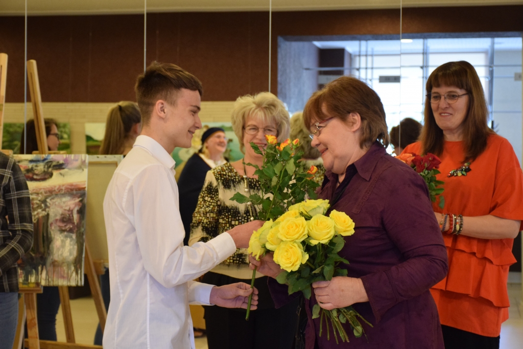 Izstādes “Viekārši galds” atklāšanā apsveikumus saņem Jaunjelgavas Kultūras veicināšanas biedrības gleznotāju domubiedru grupas iedvesmotāja un skolotāja Rasma Rinkēviča.