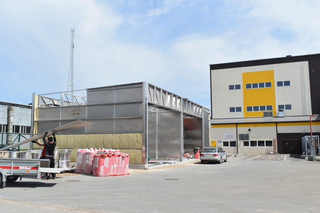 KALTE LĪDZĀS KATLUMĀJAI. Kokmateriālu žāvēšanas kalte apmēram 140 kvadrātmetru platībā (pa kreisi) top līdzās SIA “Seces koks” šķeldas katlumājai. Uz izbūvētiem pamatiem strādnieki turpina montēt rūpnieciski ražotu kaltes konstrukciju ar diviem nodalījumiem.