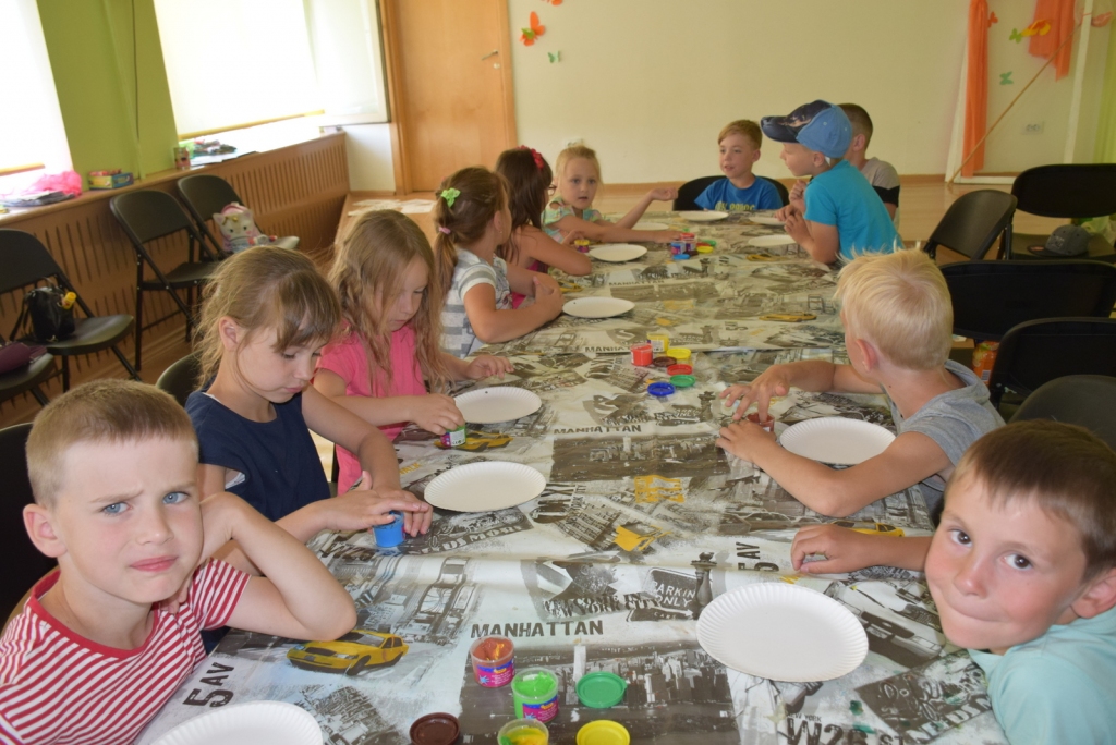 Skolotājas Agneses Leitānes vadībā bērni ar pirkstiņkrāsām zīmē mandalas.