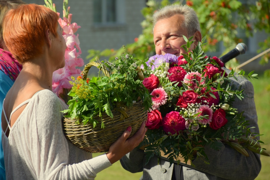 Sveiciens no kurmeniešiem. Aktierim Jānim Skanim ziedus sniedz Kurmenes tautas nama vadītāja Sarmīte Ķīse.