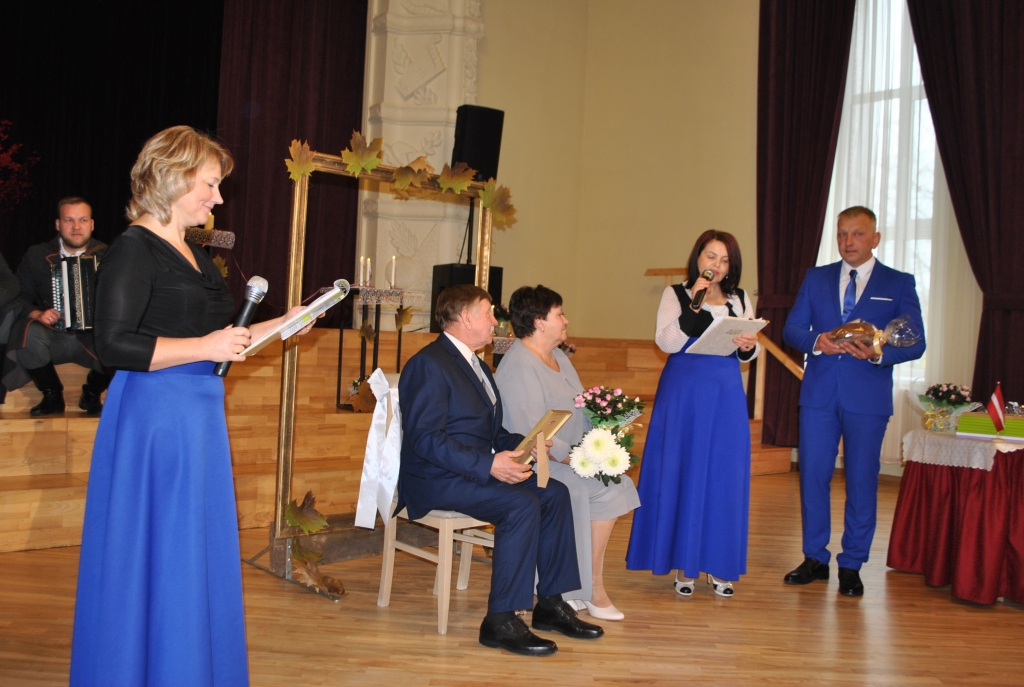 SPĒKA VĀRDI UN MAIZE sveicienā no pašvaldības. Pirmajiem apsveiktajiem  zeltkāzniekiem — Dainai un Gunāram Ēvaldam Lašiem — to dāvāja Andris Ambainis (no labās) un Vija Liepiņa.