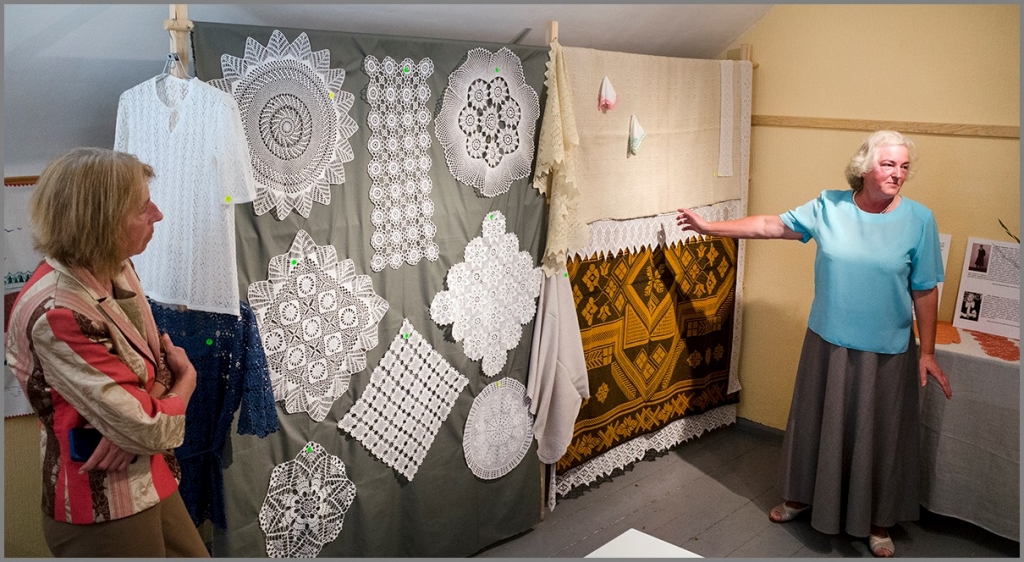 Bagātīgs pūrs. Marija Mārīte Rengarte (no labās) izstādes apmeklētājiem stāsta par māmuļas darbiem.