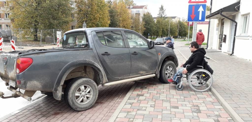Šis aizkrauklietis ratiņkrēslā ir sašutis par tādu automašīnas novietošanu. Ieskatoties uzmanīgāk, redzams, ka aizmugurējā logā kreisajā pusē ir zila zīme, kas norāda — ar šo auto brauc cilvēks ar īpašām vajadzībām.