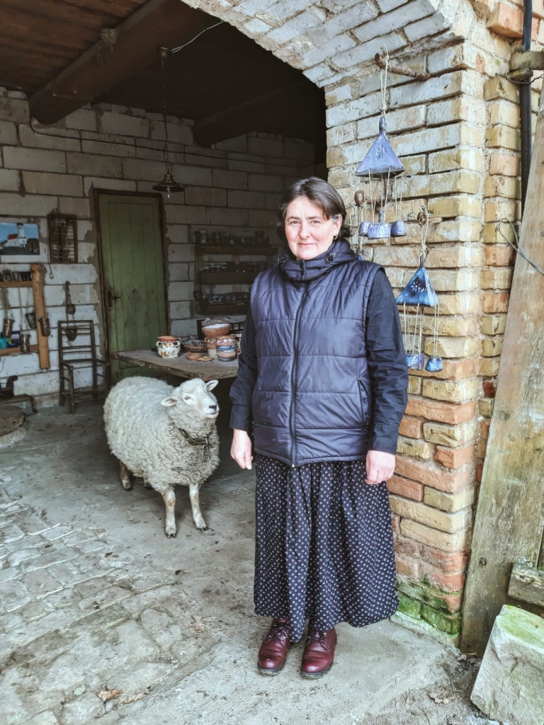 Pirms došanās uz darbnīcu. Keramiķei Zandai Ragelei no Neretas blakus vēlējās nopozēt arī aitiņa Pūka.  Pie sienas — pašas veidotie vēja zvani.
Autors: Marta Ragele