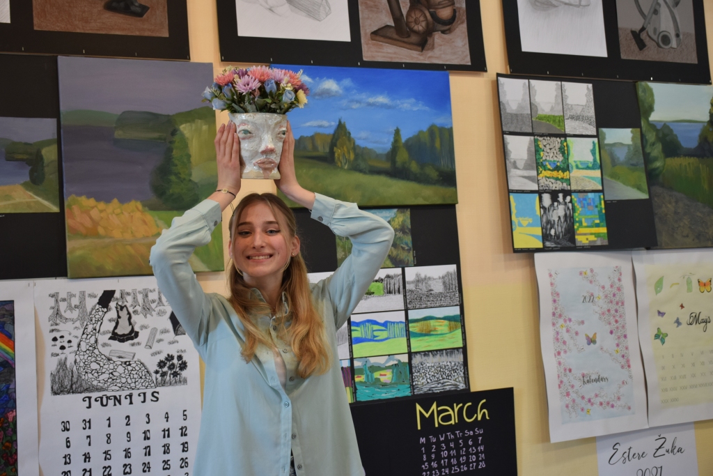 JĀVĒRTĒ PĒC LABAJĀM ĪPAŠĪBĀM. Aizkraukles Mākslas skolas absolvente Marija Gogoļa ar pašas veidoto vāzi — citplanētieti. “Lai arī citplanētieša seja ir nepievilcīga, viņa dvēsele zied kā šīs puķes. Cilvēkus vajag vērtēt nevis pēc viņu izskata, bet pēc labajām īpašībām, rakstura,” saka Marija.