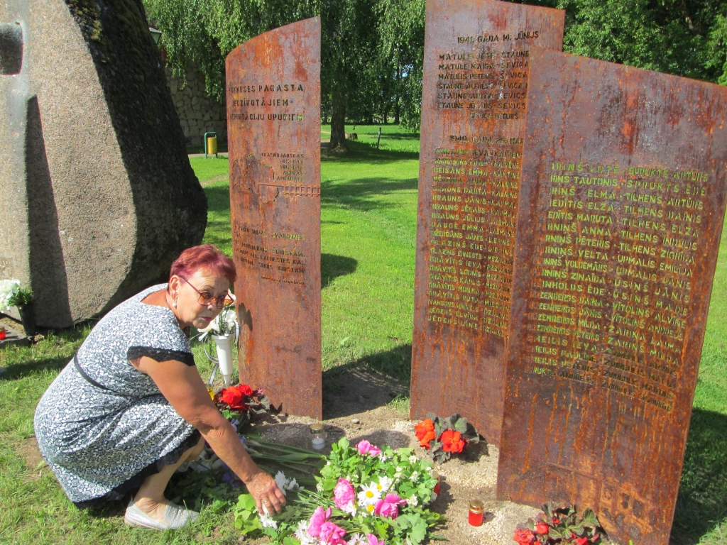 Atcerēties, lai tas neatkārtotos. Ziedus pie jaunajām piemiņas plāksnēm noliek represētā Ilga Tiltiņa.