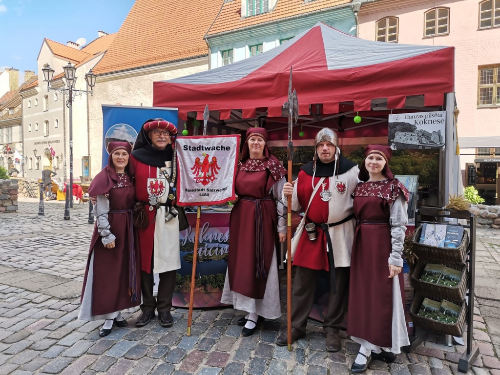 Ar moto “Kuģot gadsimtos” Rīga šogad kļuva par 41. starptautisko Hanzas dienu pilsētu. Hanzas dienu pasākumos piedalījās arī šīs senās savienības dalībniece — Kokneses pilsēta. Koknesiešu teltis atradās Rīgā, Sv. Pētera baznīcas pagalmā, kur apmeklētājus sagaidīja tūrisma informācijas speciālisti un amatnieki, kas piedāvāja dažādus suvenīrus, ražojumus un mākslinieciskus darinājumus.
Attēlā — Kokneses tūrisma centra meitenes tikušas pie kavalieriem no Vācijas  pilsētas Zaltsvēdeles.
Autors: no Kokneses tūrisma centra